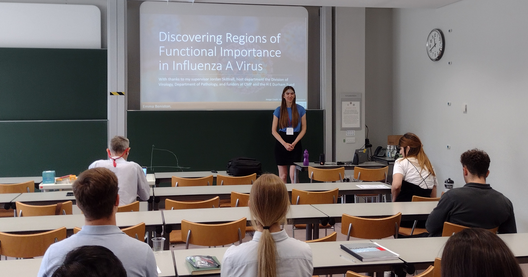 Emma Beniston standing in front of a screen with a presentation, with an audience in the foreground